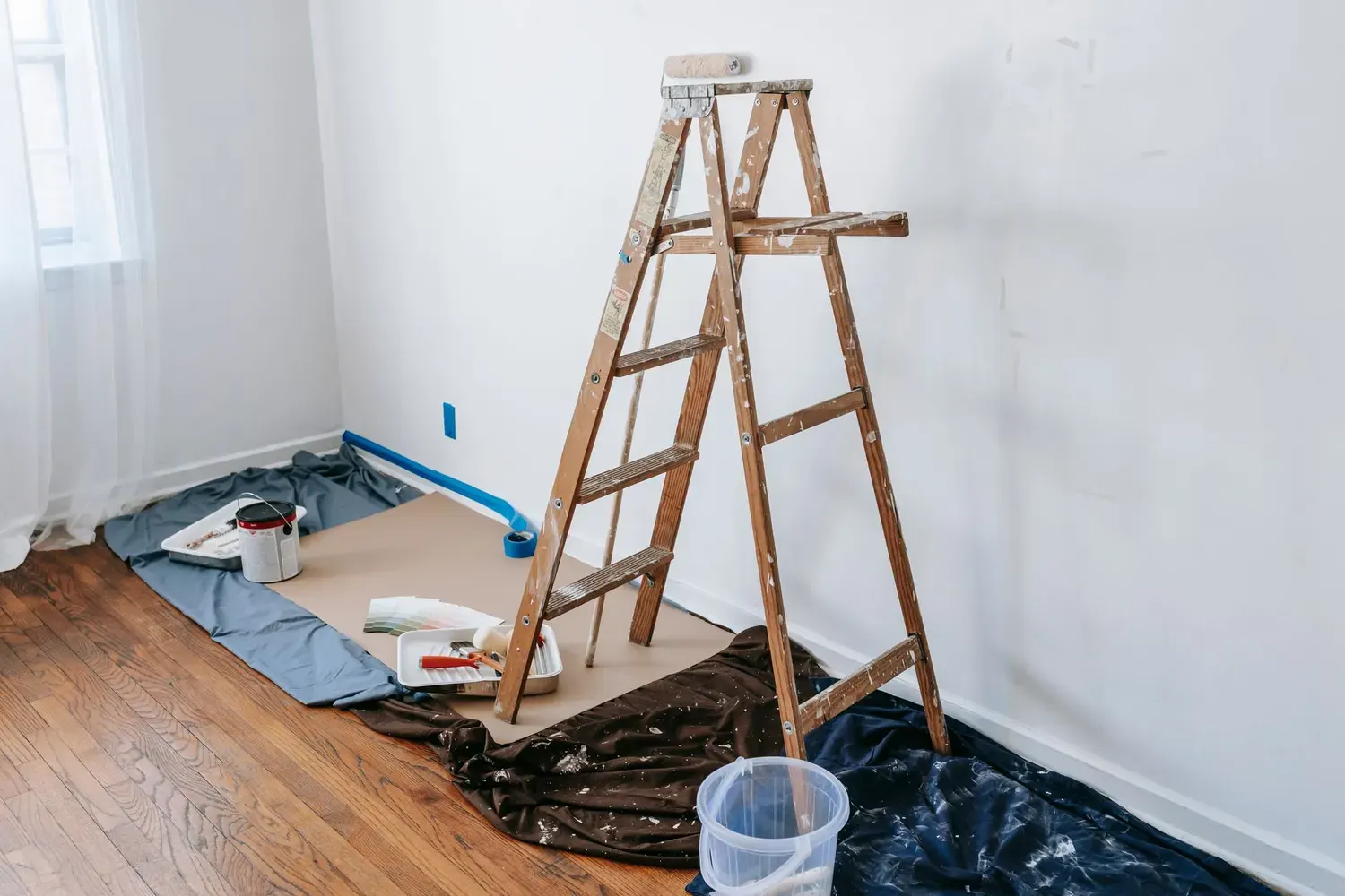 Interior painting in Marietta, GA: stepladder, drop cloths and paint supplies set up in an empty room