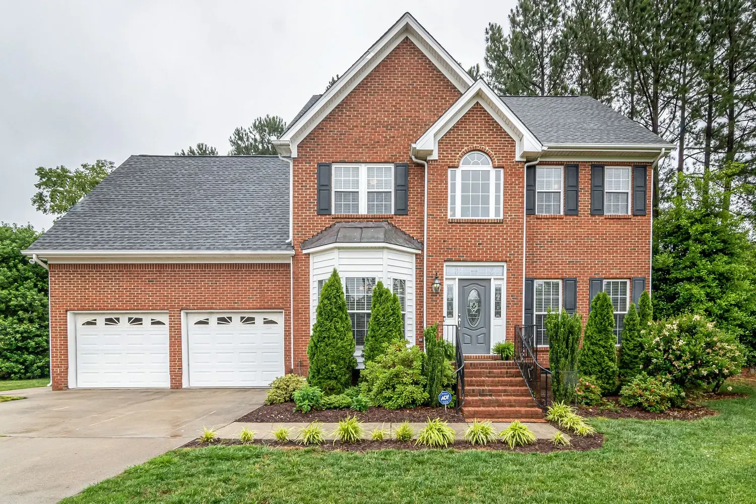Painter in Sandy Springs, GA: two-story brick home with landscaping and a front entry